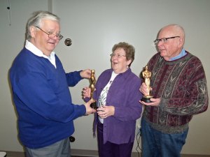 photo by Dennis Dalman Stunned by surprise, Jan Sorell accepts a best-actress Oscar from John Augustin for her role in "The Senior Connection." At right is Bill Morgan, who won the best-actor Oscar for his performance, also in "The Senior Connection," an intriguing mystery movie about a group of people, mainly elderly, who live in a Minnesota city named Sartell. Augustin, a former Sartell science teacher and long-time Oscar buff, invited his audience to pose and have fun spoofing with his "prop" Oscars after his talk about the history of the Academy Awards. Augustin was guest speaker for the weekly Thursday talk, Feb. 13, sponsored by the Sartell Senior Connection.