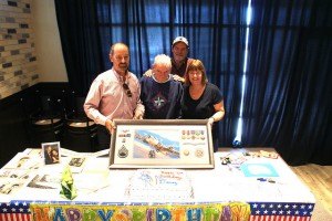 contributed photo At his 90th birthday party at House of Pizza in Sartell, Dewey “Sully” Sullivan and his sons and daughter gather at the mementoes table, which displayed old photographs, World War II medals and of course a birthday cake. From left to right are Mike Sullivan, Pat Sullivan and Colleen (Sullivan) Schwegel. 