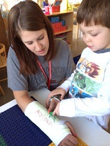 contributed photo Brayden Klinkner practices letter formation on a pretend cast on the arm of reading tutor Kara Rud. The cast was part of a demonstration from a visiting surgeon at the school who explained to the children how casts work to help heal broken bones.