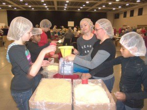 photo by Dennis Dalman Children and an adult mix and pour food-bag ingredients through a funnel into a bag at the We Are Thankful event in St. Cloud Nov. 22. From left to right (clockwise) are Morgan Voelker, Silas Larsen, Alex Voelker, Mikayla Voelker, Krista Voelker and Titus Larsen. The Larsens are from St. Cloud, the Voelkers hail from St. Augusta. 