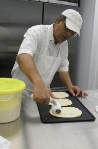 photo by Logan Gruber A customer ordered some No-nonsense Naan Monday night, and Tahir Sandhu can be seen here stamping it and placing it in the oven.