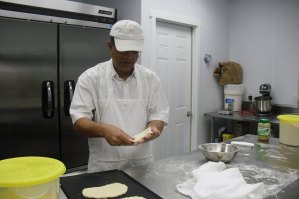 photo by Logan Gruber A customer ordered some No-nonsense Naan Monday night, and Tahir Sandhu can be seen here forming it before stamping it and placing it in the oven.