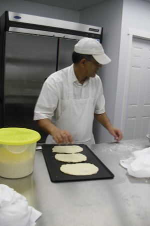 photo by Logan Gruber A customer ordered some No-nonsense Naan Monday night, and Tahir Sandhu can be seen here forming it before stamping it and placing it in the oven.