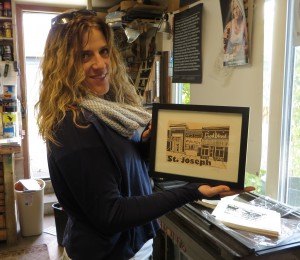 photo by Cori Hilsgen Mary Bruno holds a print of downtown St. Joseph which is also featured in her new 2015 "Best Minnesota Hometown" calendar. Both will be available at the annual holiday art sale Dec. 6.   