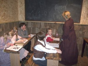 photo by Dennis Dalman Ebenezer Scrooge as a boy, (front) watches as his teacher writes the words “Merry Christmas” on the chalkboard. Shortly after, the teachers will inform him, sadly, that his family has been placed in a debtor’s prison. 