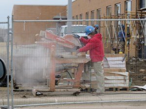 photo by Logan Gruber Construction at Kennedy Community School continues, as workers finish up parts of the brick facade. A worker can be seen here using a miter saw to cut the bricks to size on Monday morning.