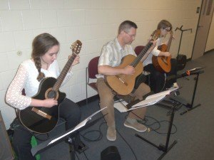 photo by Dennis Dalman Three guitarists perform Chim-Chim-Cher-ee, a song from the musical Mary Poppins, at the Pine Groove Festival April 25 at Sartell Middle School. From left to right are guitar student Celia Merton of St. Cloud, her teacher Kevin Carlson of St. Cloud and Emma Douglas of Annandale. Erickson is the owner of PMI Guitar School, St. Cloud. 