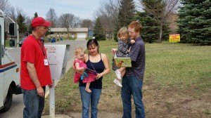 photo by Logan Gruber U.S. Postal Service delivery driver Todd Ruegemer, Cold Spring, had the honor of delivering the book to Layla Hawkins, 15 months. Ruegemer also delivered a book to Layla's sister, Amyra Hawkins, at the same time. Parents Chantal and Cole Hawkins held the girls during the delivery.