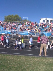 photo by Dennis Dalman Students carrying placards walk down the track to positions on the football field where they surprised departing Sartell Middle School Principal Julie Tripp during a rally.