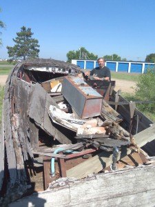 photo by Dennis Dalman What looks like a heap of rubble is actually a classic Chris Craft wooden boat, vintage 1954. David Watts (in photo), the owner of Little Rock Boat Works in Rice, actually restores such old battered boats to their original shine and authenticity. 
