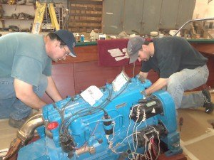 photo by Dennis Dalman Wayne Carriveau (left) and Scott Hinkle work on a boat moter inside a 1957 Chris Craft boat at Little Rock Boat Works in Rice. 