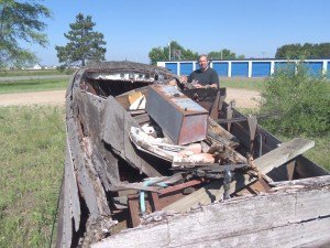 photo by Dennis Dalman What looks like a heap of rubble is actually a classic Chris Craft wooden boat, vintage 1954. David Watts (in photo), the owner of Little Rock Boat Works in Rice, actually restores such old battered boats to their original shine and authenticity. 