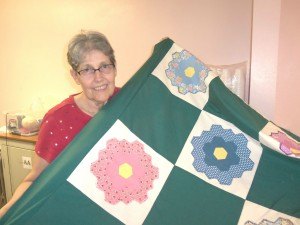 photo by Dennis Dalman Nancy Anderson holds up one of the colorful quilts her group makes for good causes. Anderson is a former mayor of Rice.