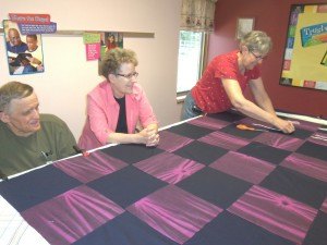 photo by Dennis Dalman Jim and Ardelle Amundson of Sartell (left and center) and Nancy Anderson work on a patchwork quilt at Good Shepherd of the Pine Church. The quilting group meets at various places throughout the year in Rice, Sauk Rapids and Sartell. They create up to 2,000 quilts and never sell a one of them. They all go free to good causes.