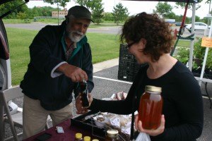 photo by Steven Wright Paul Warpeha of Milaca shows Denise Honkomp his homemade maple syrup and honey at CentraCare's Farmer's Market on Thursday June 11.
